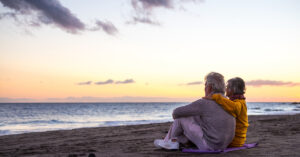 Anal Cancer: a mature couple sitting on a beach watching the sunset.
