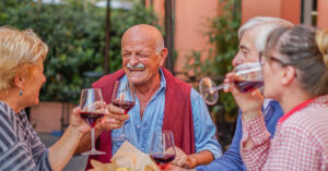 Two elder couples out at dinner socializing with wine.
