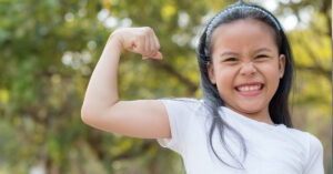 Happy little asian child showing arms muscles.