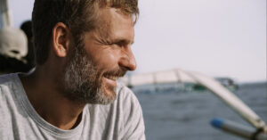 A middle-aged man is traveling by sea in a boat.