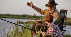 An elder man teaching a child to fish.