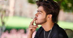 A photo of a young adult male, smoking a cigarette. Maleusers of tobacco products are a high-risk demographic for developing Oral Cancer.