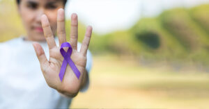 Woman holding purple ribbon to supporting people living with pancreatic cancer.